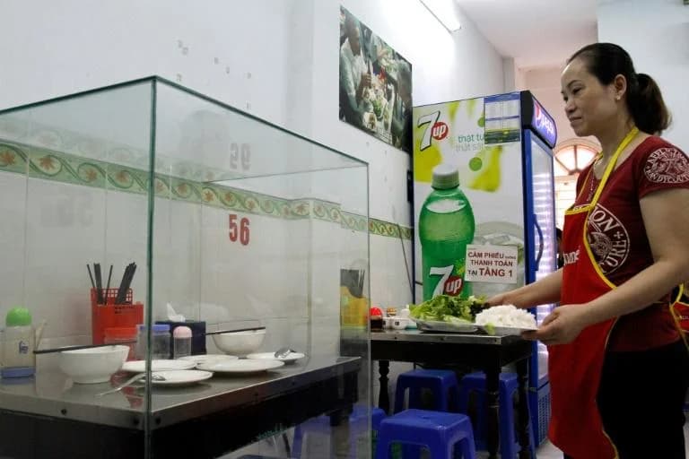 The table used by Obama and Bourdain preserved behind glass at Bún Chả Hương Liên